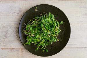 Top view of vegan healthy salad made of peas microgreen sprouts and sprouted beans on wooden background photo