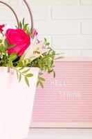 Minimalism style greeting card with text Hello, Spring on the pink letter board and beautiful fresh flowers on light brick background. photo