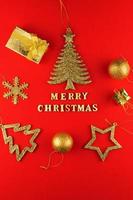 Festive greeting card. Merry christmas lettering on red paper with golden glittering toys. photo