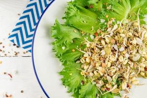 Top view of vegan healthy salad made of peas microgreen sprouts and sprouted beans on wooden background photo