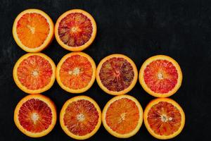 Beautiful background made of blood orange slices in a rows on black background. photo