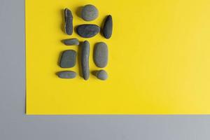 Flat lay in a trendy 2021 new colors. Illuminating Yellow and Ultimate Gray. Color of the Year 2021. Grey sea stones on yellow background. photo