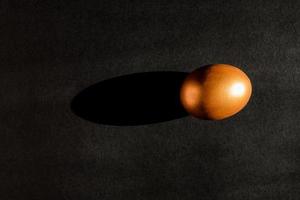 Easter concept. A golden egg on black background with shadow light. Top view with copy space photo