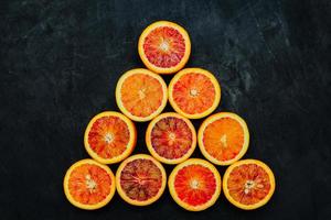 Beautiful background made of blood orange slices on black stone surface. photo