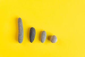 Flat lay in a trendy 2021 new colors. Illuminating Yellow and Ultimate Gray. Color of the Year 2021. Grey sea stones on yellow background. photo