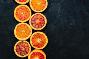 Sliced Sicilian blood oranges on black stone natural background, top view. photo