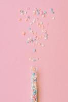 asperja granulado. dulce confeti. fondo rosa para diseños de vacaciones, fiesta, cumpleaños foto