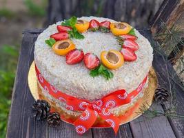 Homemade layer cake Napoleon decorated with strawberry and halves of apricot on wooden rustic background photo