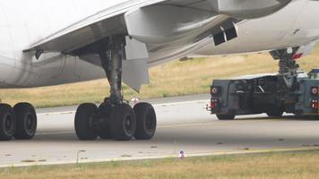 Close up of the landing gear wheels, tyres on a modern twin engined passenger aircraft. Aircraft is taxiing along the airport apron. video