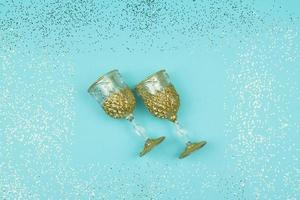 Two empty champagne glasses on blue sparkling background. Festive greeting card with confetti. photo