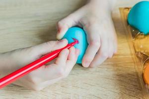 Child hand painting easter egg with felt-tip pen. Close up photo