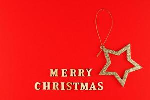 tarjeta de felicitación festiva. letras de feliz navidad sobre fondo rojo con estrella dorada brillante. foto