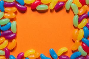 Assorted Jelly Beans border with copyspace on orange background. photo