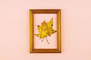 Autumn bouquet of golden painted maple leaves on pink background. Trendy concept. Flay lay in minimalism style. photo