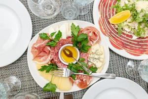 mesa festiva, cena familiar con antipasti italiano servido: salmón marinado, jamón, carpaccio, pera, albahaca. paisaje de mesa foto