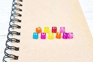 Side Hustle words made form multicolored square beads on spiral notebook cover. Concept image of passive income photo
