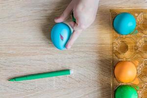 Child hand painting easter egg with felt-tip pen. Top view photo