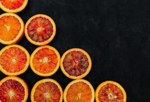 Organic Raw Red Blood Oranges in a rows on a black background. Copy space for text. photo