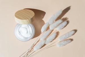 Cream jar and moisturizer on beige background. Beauty facial cosmetic product texture top view. Body care lotion photo