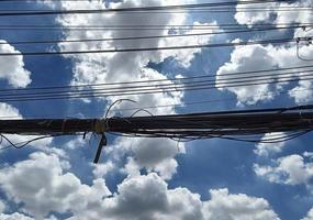 messy electricity wires on the pole, straight line of cables and wires on an electric pole in Thailand, sky and clouds background photo