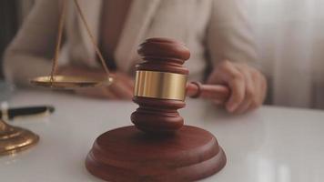 Justice and law concept.Male judge in a courtroom with the gavel, working with, computer and docking keyboard, eyeglasses, on table in morning light video