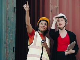 Diverse group of people working together at container terminal. Female African American foreman and industrial engineer woman manager standing at container depot. Diversity business people concept. photo