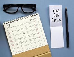 December 2022 desk calendar with Year End Review text written on notepad. photo