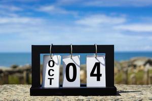 Oct 04 calendar date text on wooden frame with blurred background of ocean. photo