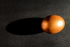 Easter concept. A golden egg on black background with shadow light. photo