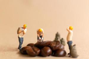 equipo de trabajadores en miniatura trabajando con granos de café foto