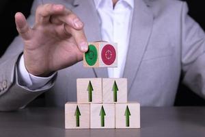 Growth or business concept. Arrow icon on wooden cubes and target, target, on wooden cubes on the background of a businessman in a gray suit sitting at the table. photo