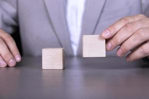 A businessman holds two wooden cubes with empty space for icons, free space for letters, numbers, symbols or labels. photo