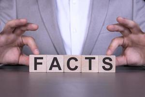 FACTS, the word is written on wooden cubes, blocks on the background of a man, a businessman in a gray suit. photo