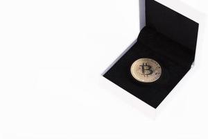 Gold bitcoin in a white gift box with black velvet on a white background. Copy space. photo