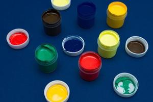 Close up of open acrylic paint cans. Colorful paints on blue background photo