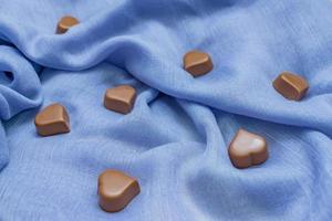 corazones de chocolate con leche sobre tela azul. fondo de vacaciones de san valentín. concepto de amor foto