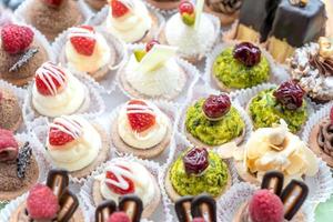 Pastry shop display window with variety of mini desserts and cakes, candy bar, selective focus. photo