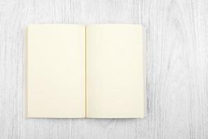 Open brown notebook and a pencil on white wooden table, top view photo