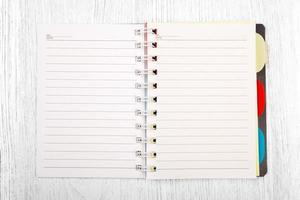 Open notebook and a pencil on white wooden table, top view photo