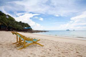 Beach chairs on the white sand beach with cloudy blue sky photo