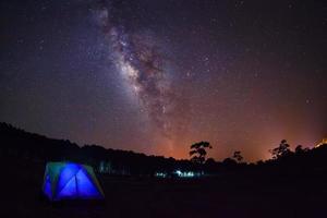 Silhouette of Tree with Tent and Milky Way at Phu Hin Rong Kla National Park,Phitsanulok Thailand. Long exposure photograph. photo