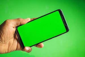 mano que sostiene el teléfono inteligente de pantalla verde foto