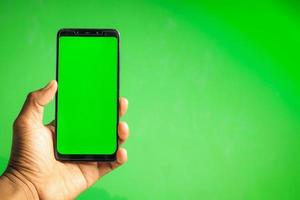 mano que sostiene el teléfono inteligente de pantalla verde foto