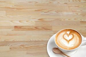 A cup of coffee latte with spoon on wood blackground photo