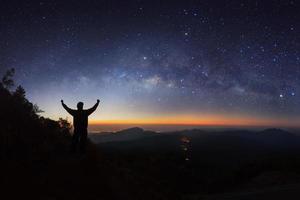milky way galaxy and silhouette of a standing happy man on Doi inthanon Chiang mai, Thailand. photo