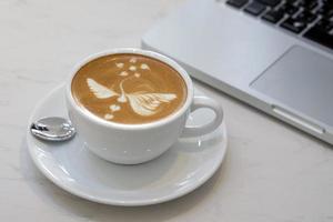 coffee latte art with laptop in coffee shop photo