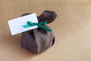 sack gift bag with ribbon bow on brown background photo