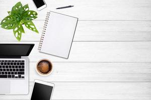 Modern workspace with laptop tablet, smartphone and coffee cup copy space on white wood table background. Top view. Flat lay style. photo