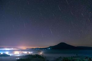 meteoro gemínido en el cielo nocturno con luna y niebla en el punto de vista de khao takhian ong en khao-kho phetchabun, tailandia foto