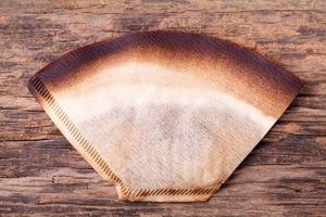 Coffee filter with brewed coffee on wood background photo